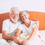 uomo e donna sorridenti seduti sul letto