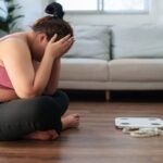 ragazza seduta a terra nel salone con le mani in testa