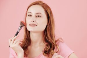 Donna dai capelli rossi che applica blush con pennello