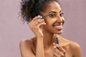 Donna sorridente che applica il mascara