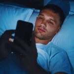 ragazzo guarda lo smartphone a letto