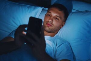 ragazzo guarda lo smartphone a letto