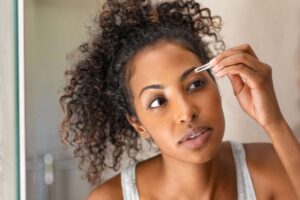 Donna che strappa le sopracciglia con la pinzetta